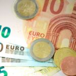 Detailed shot of Euro banknotes and coins showcasing currency denominations.