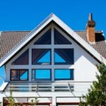A modern A-frame house with large windows against a clear blue sky, showcasing contemporary architecture.
