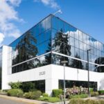 Contemporary office building in Redmond with reflective glass and lush greenery, captured on a sunny day.